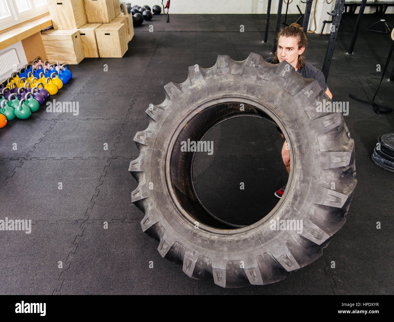 Photo d'un séduisant jeune homme travaillant sur avec un tracteur tire dans une salle de sport. Banque D'Images
