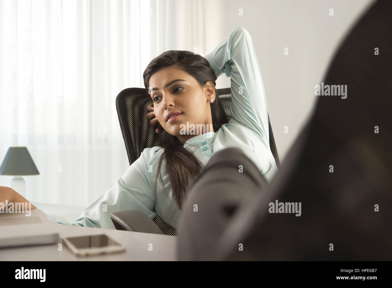 Portrait of a businesswoman at 24 avec ses pieds et de travailler sur un ordinateur portable Banque D'Images