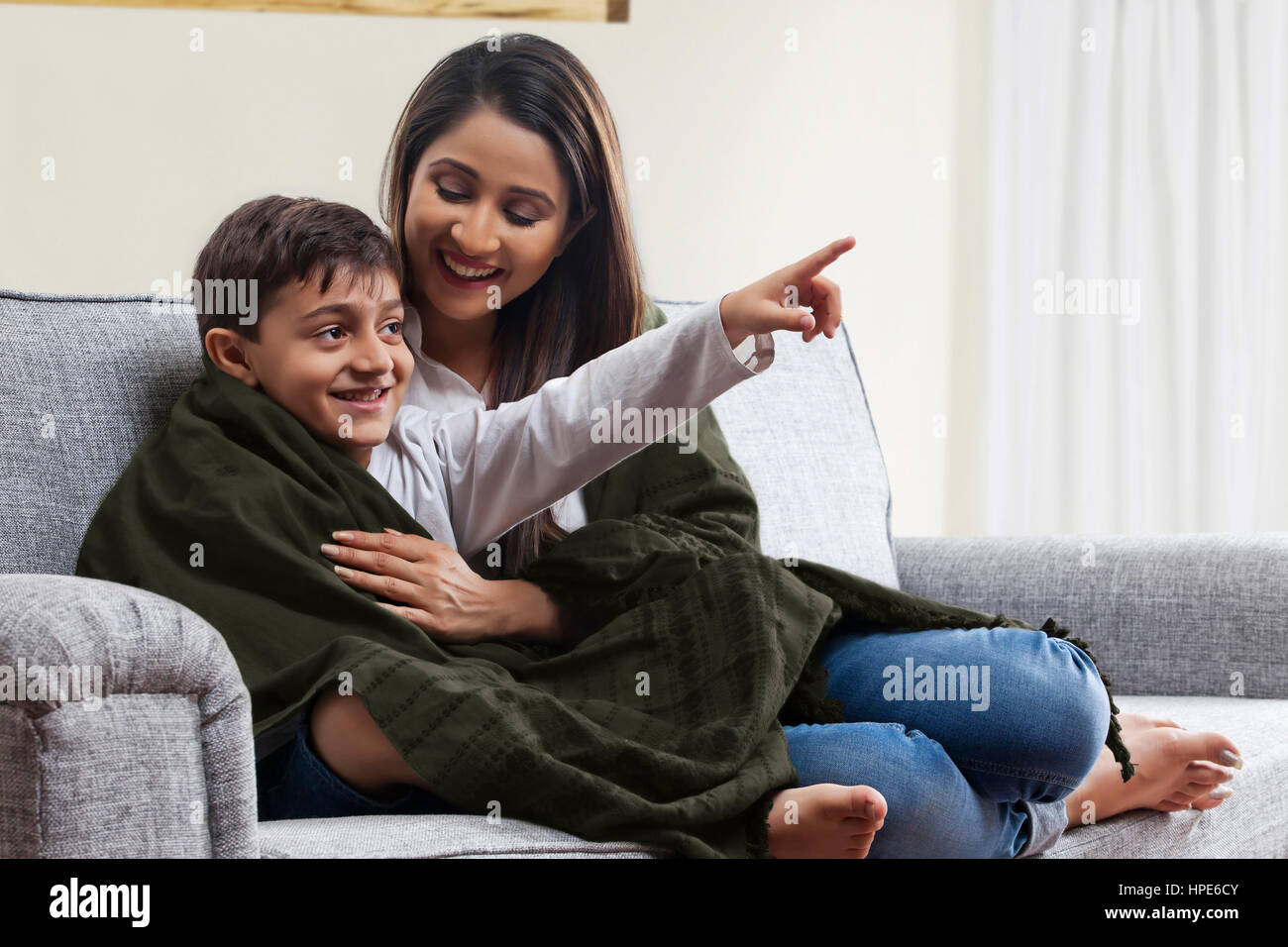 Smiling mother and son enveloppé dans une couverture devant la télé sur canapé Banque D'Images