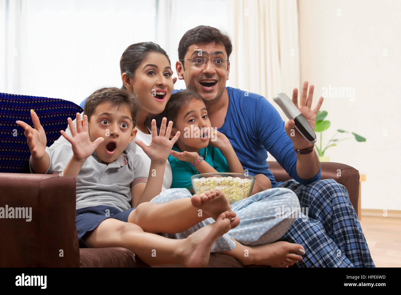 Famille en pyjama à regarder la télévision et eating popcorn Banque D'Images