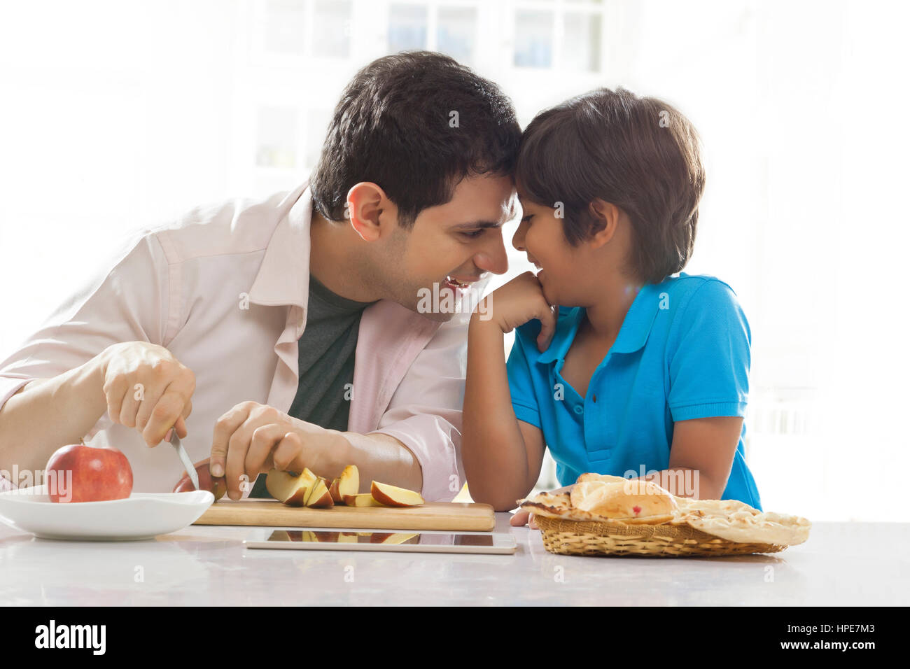 Père et son fils souriant de chefs ensemble à table du petit déjeuner Banque D'Images