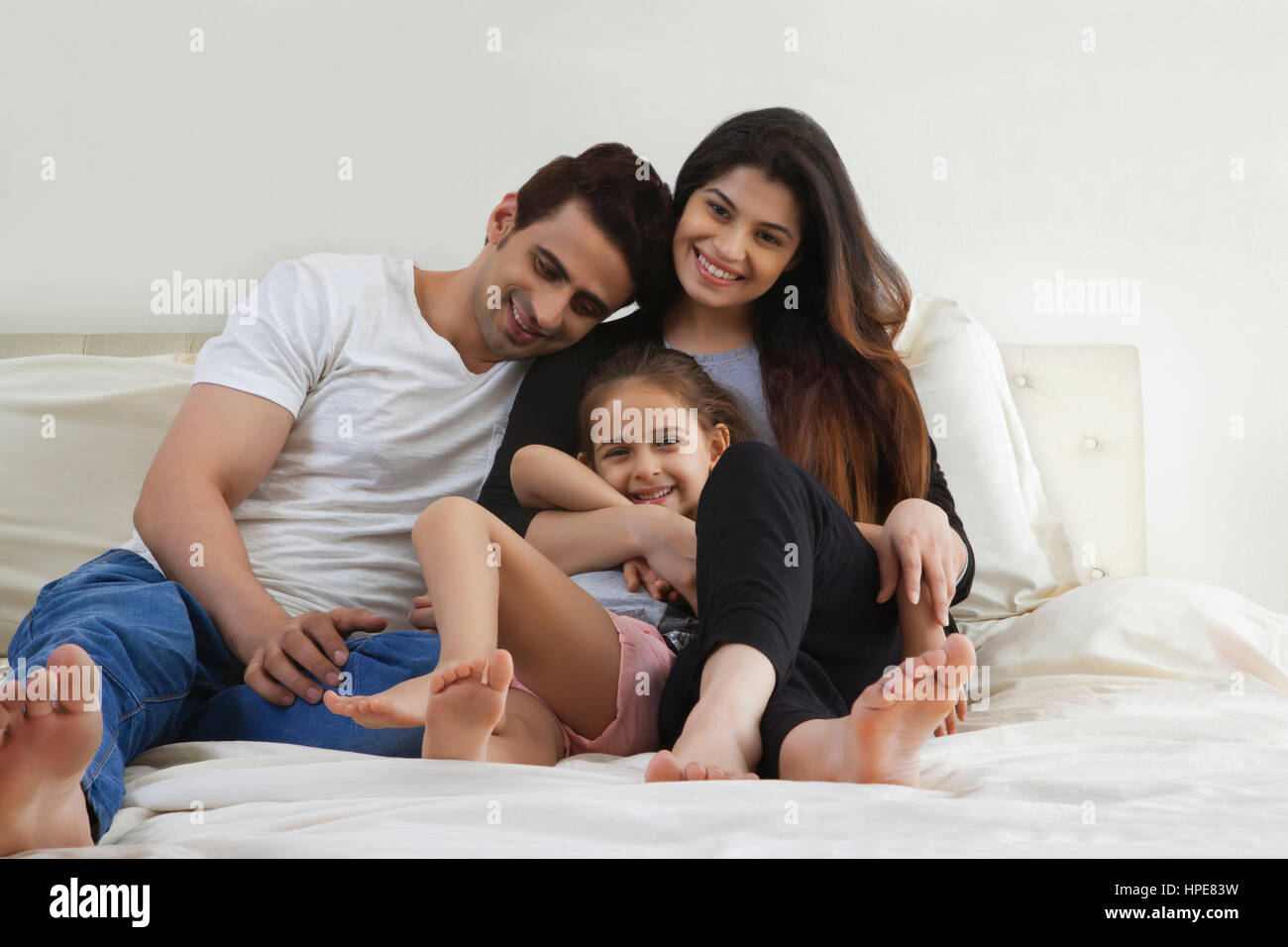 Smiling parents with daughter sitting on bed Banque D'Images