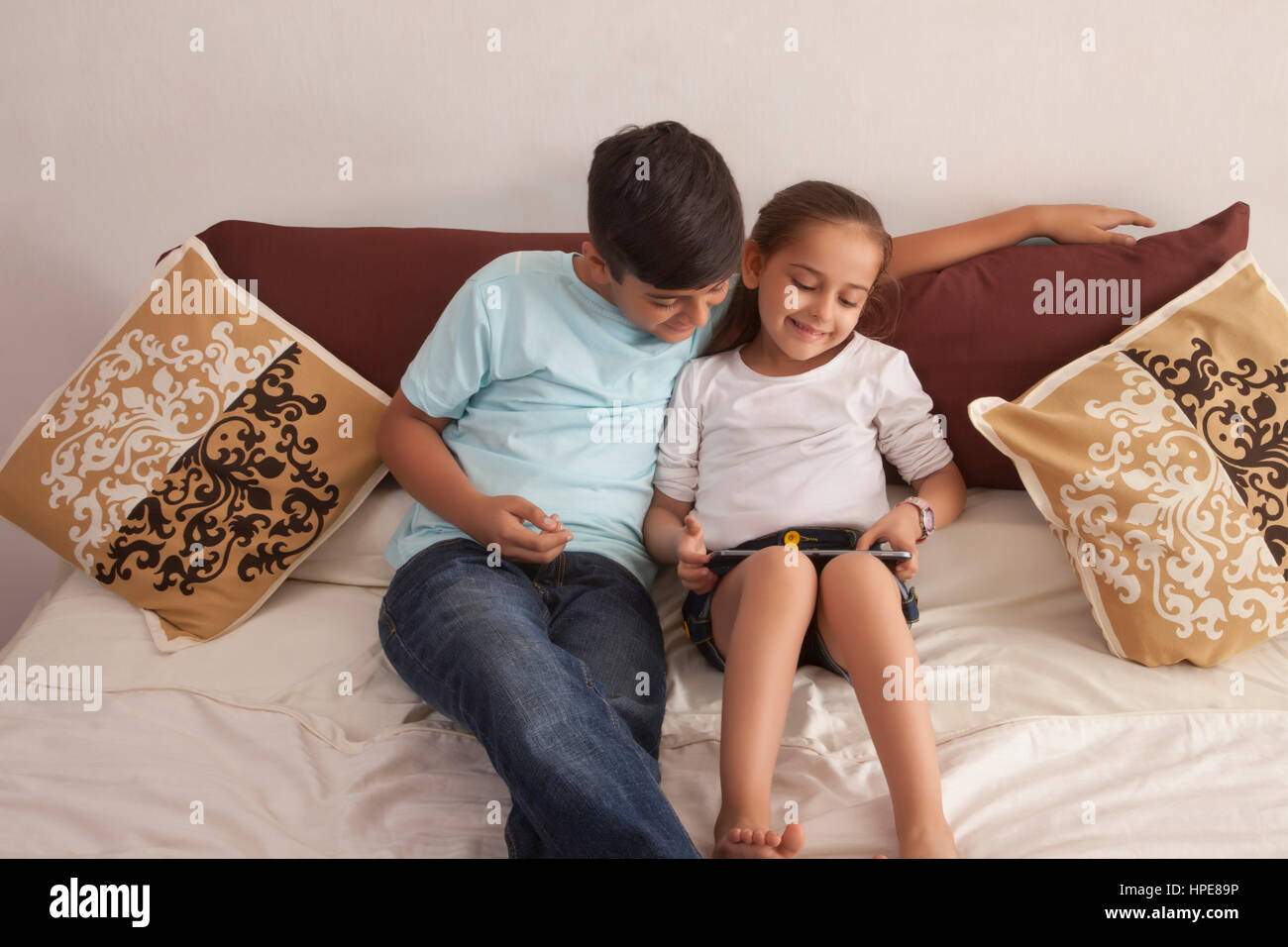 Brother and sister using digital tablet in bedroom Banque D'Images