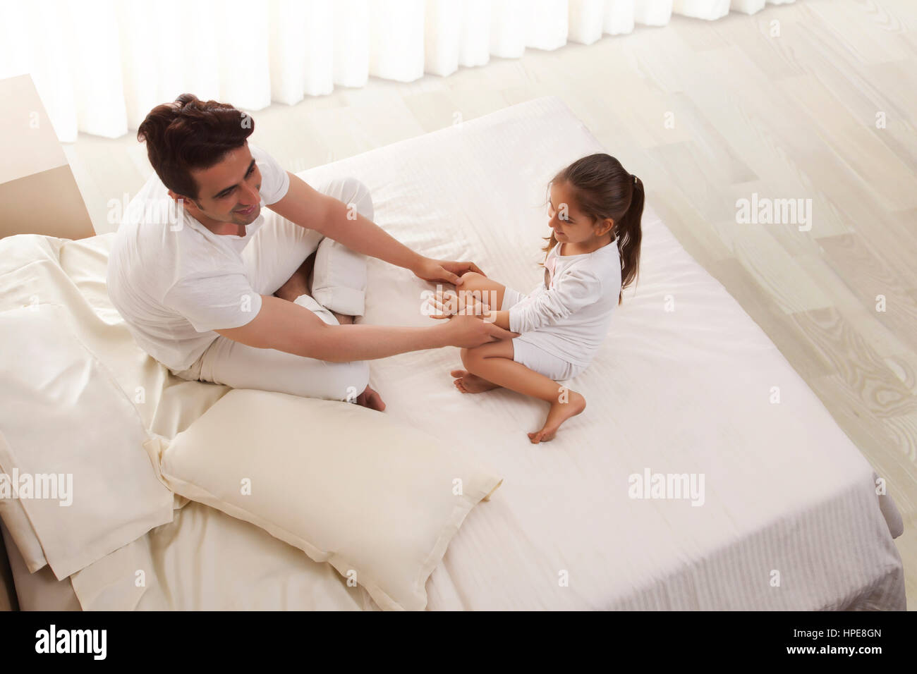 Père et fille assis sur le même lit Banque D'Images