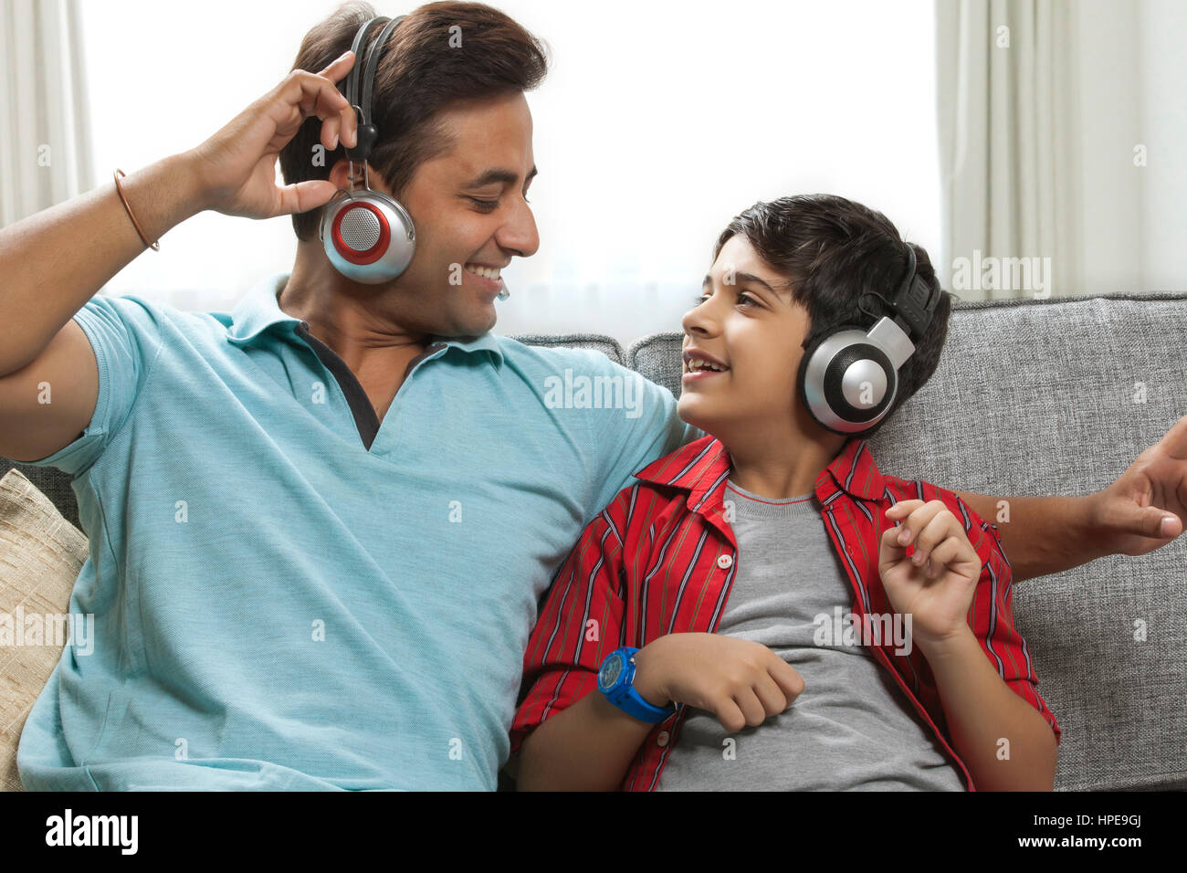 Père et fils d'écouter de la musique ensemble sur canapé avec un casque Banque D'Images