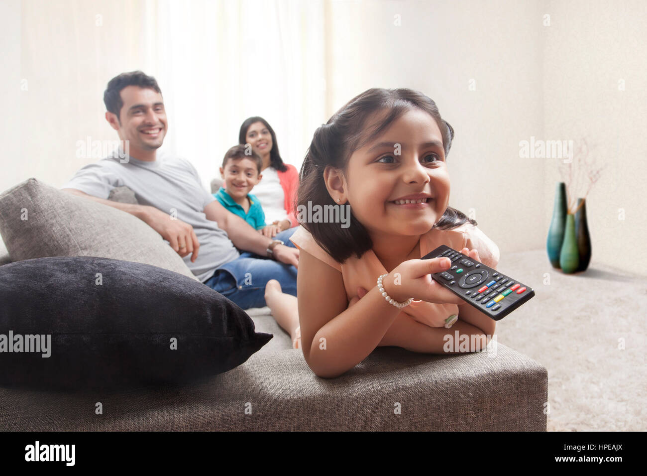 Souriante jeune fille regarder la télévision en famille Banque D'Images