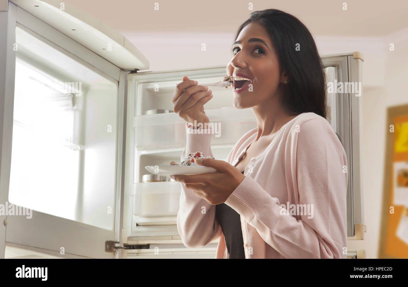 Close-up of young woman standing in front of open réfrigérateur de pâtisserie de l'alimentation Banque D'Images Close-up of young woman standing in front of open réfrigérateur de pâtisserie de l'alimentation Banque D'Images