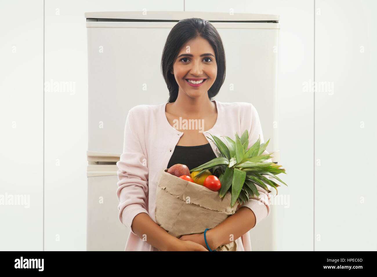 Jeune femme debout devant un sac de fruits de réfrigérateur Banque D'Images