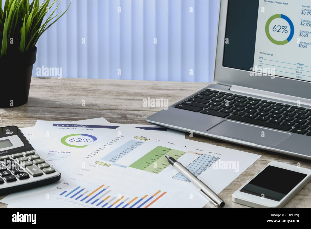 Travail moderne au bureau : les tirages de cartes et de données financières à côté d'un ordinateur portable, smartphone et calculateur sur le bureau. Banque D'Images