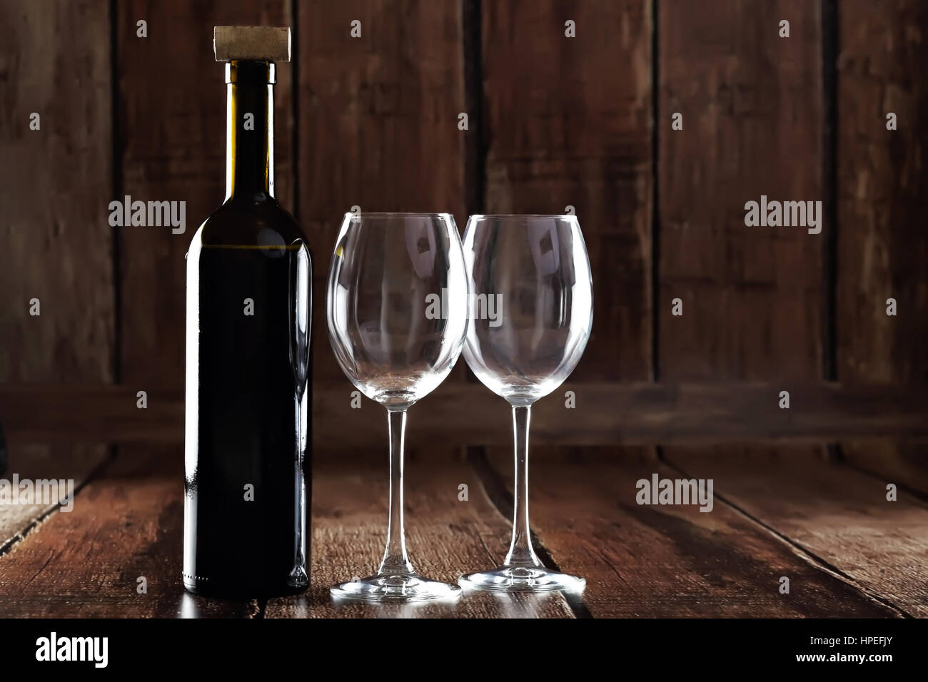 Bouteille de vin rouge et deux verres vides sur fond de bois Banque D'Images