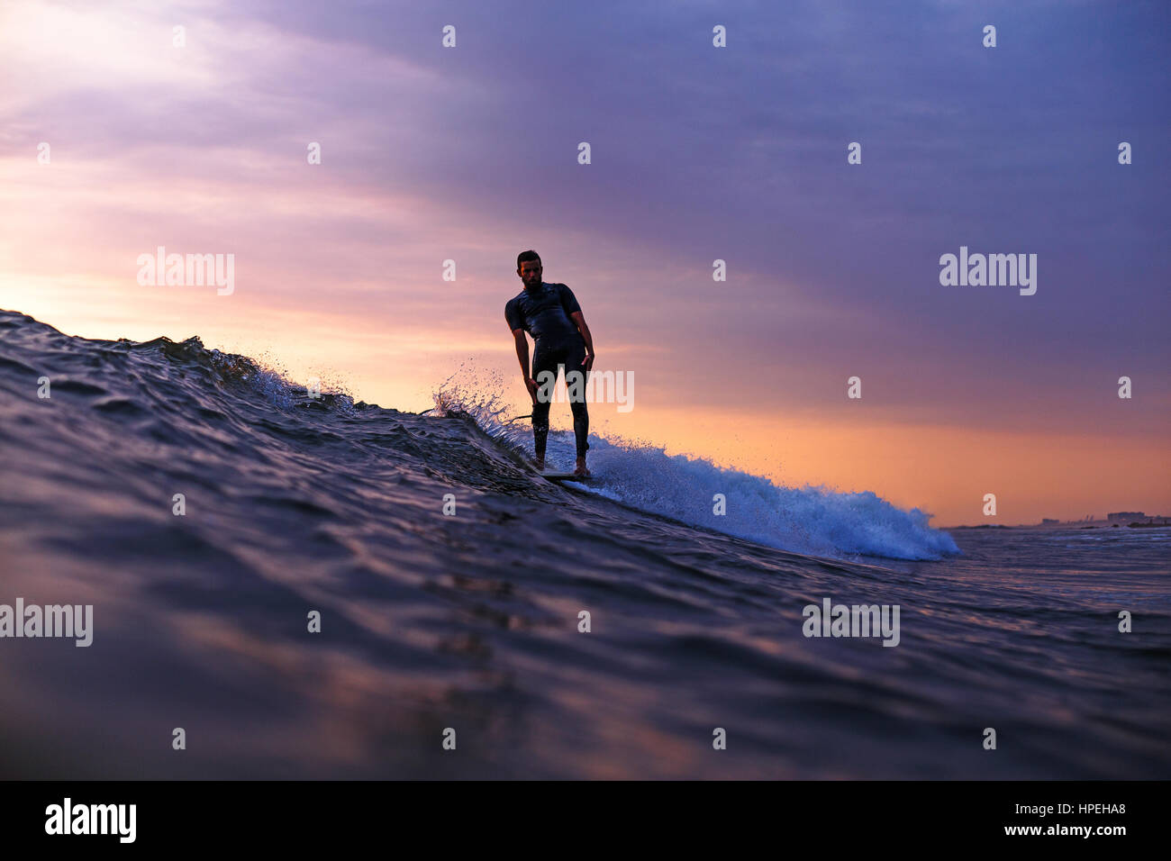 Surfer sur une vague de faire une manœuvre au coucher du soleil Banque D'Images