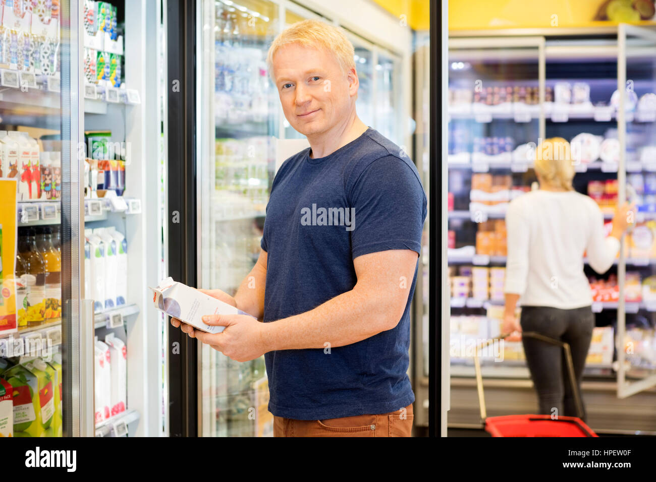 Portrait of mature male customer holding juice paquet lors de l'article in grocery store Banque D'Images