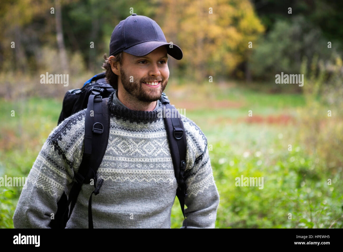 Smiling Young man with backpack hiking in forest Banque D'Images