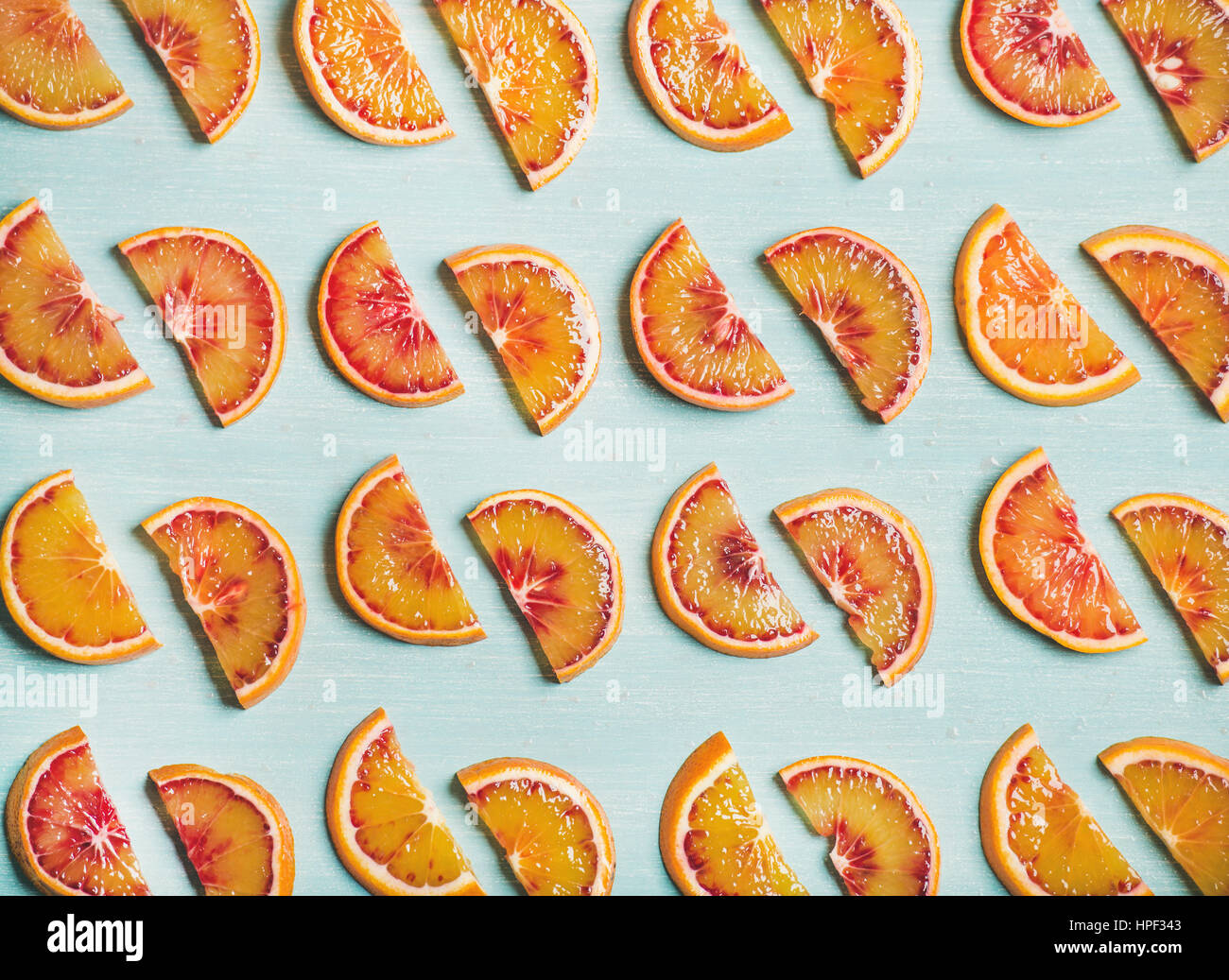 Modèle des fruits naturels concept. Les tranches d'orange sanguine juteuse douce peintes en bleu clair sur fond de table, vue du dessus Banque D'Images