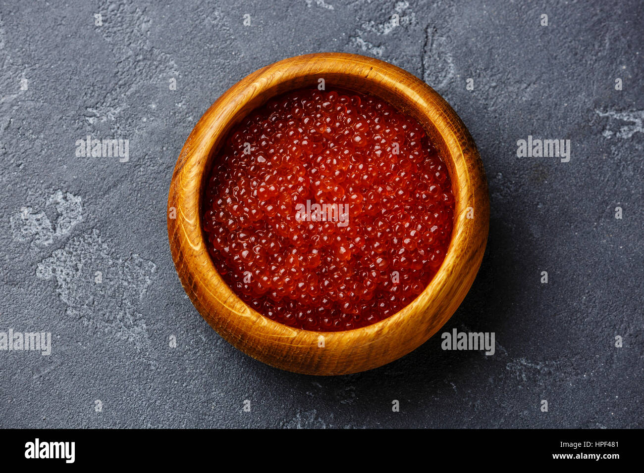 Caviar de saumon rouge dans le bol en bois sombre sur fond de pierre Banque D'Images