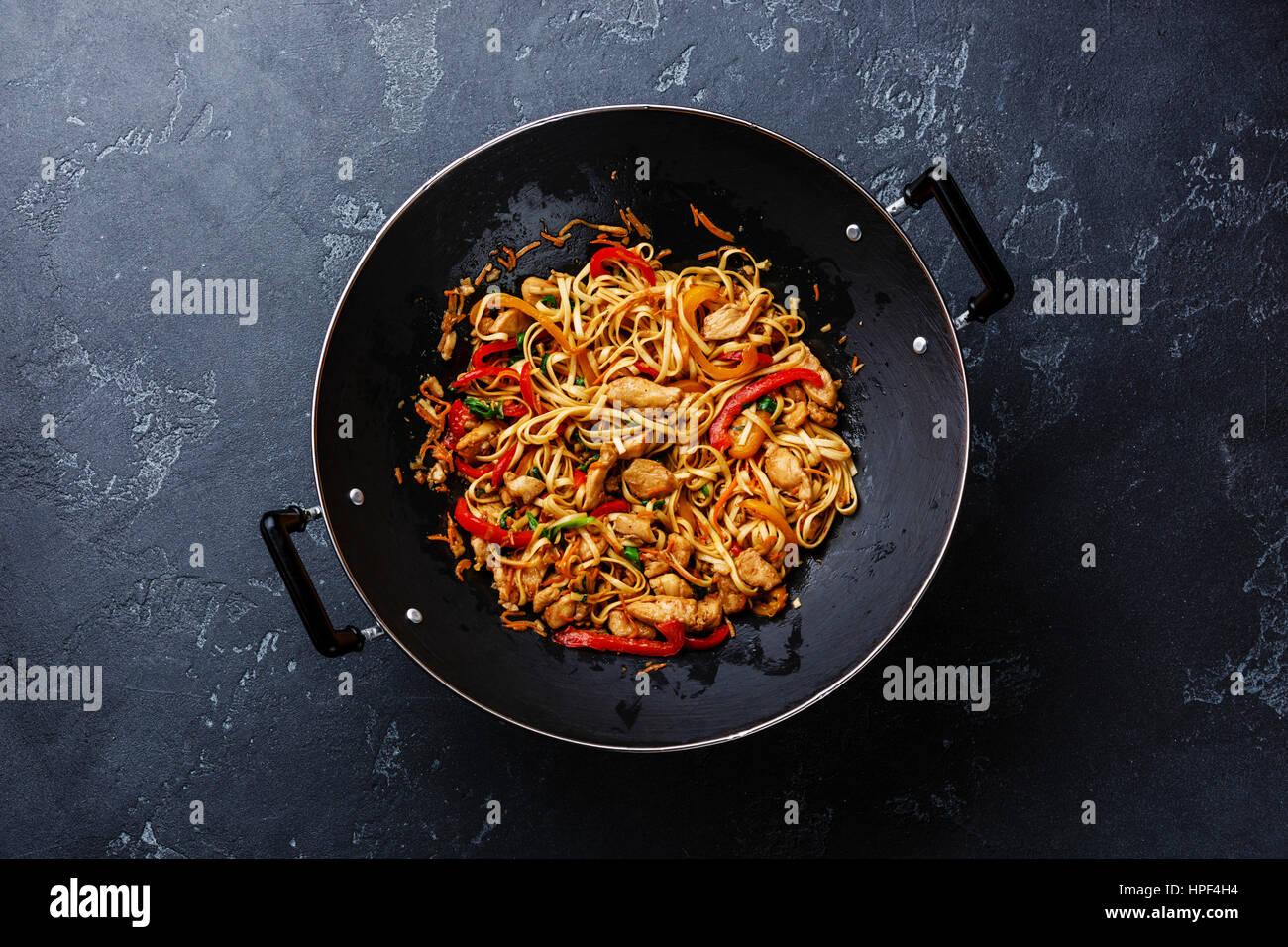 Udon nouilles sauté au poulet et légumes en wok casserole sur fond noir en sombre Banque D'Images