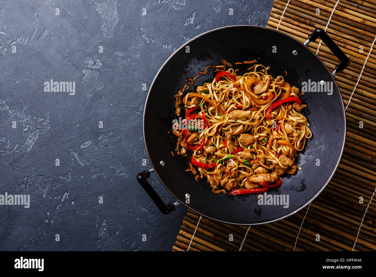 Udon nouilles sauté au poulet et légumes en wok casserole sur pierre sombre contexte copy space Banque D'Images