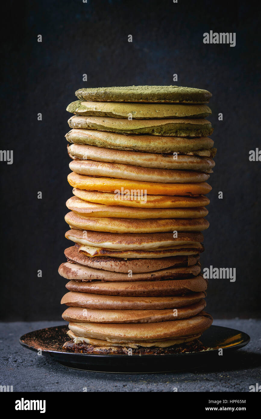 Pile haute en couleur de l'ombre de l'Amérique faite maison, chocolat et matcha thé vert curcuma crêpes sur plaque sur pierre noire texture background. Banque D'Images