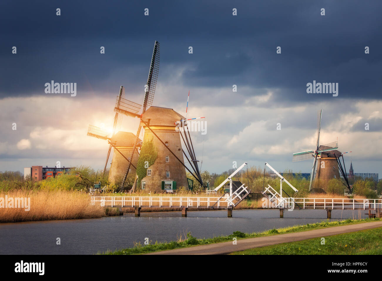 Les moulins à vent contre ciel nuageux au coucher du soleil à Kinderdijk, célèbre aux Pays-Bas. Paysage rustique avec moulins à vent traditionnel néerlandais, pont, l'eau et le ciel Banque D'Images