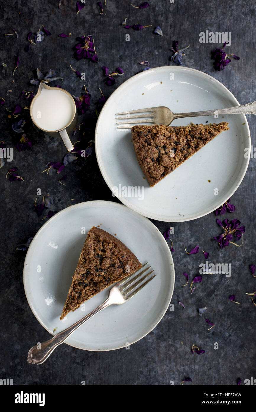 Deux tranches de gâteau de miettes de sésame noir servi avec de la crème. Photographié sur fond gris/noir. Banque D'Images