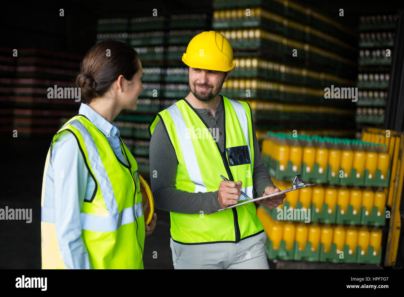 Les ouvriers d'usine discuter sur presse-papiers à l'usine de production de boissons Banque D'Images