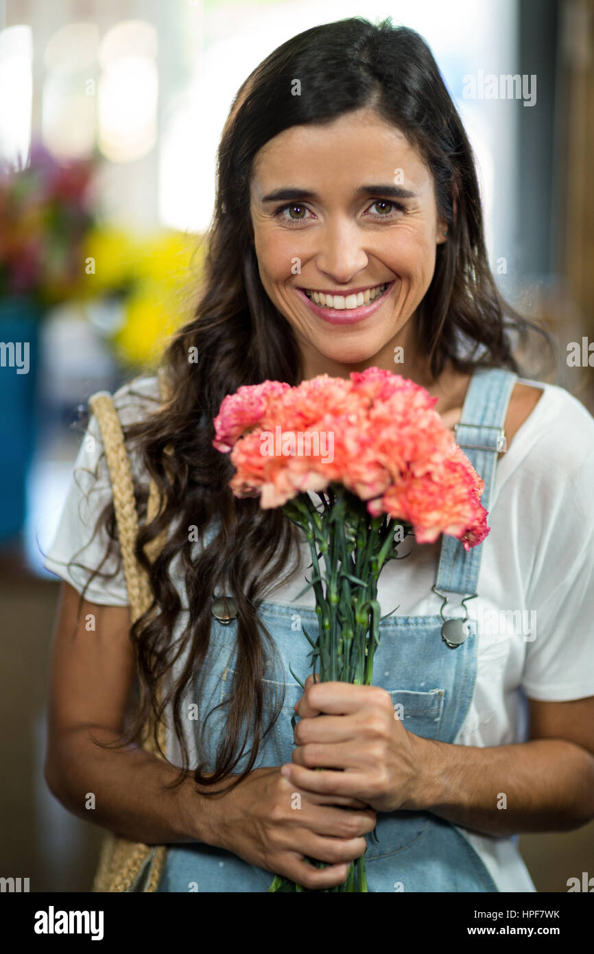 Portrait of a smiling woman holding a bouquet de fleurs à un fleuriste Banque D'Images