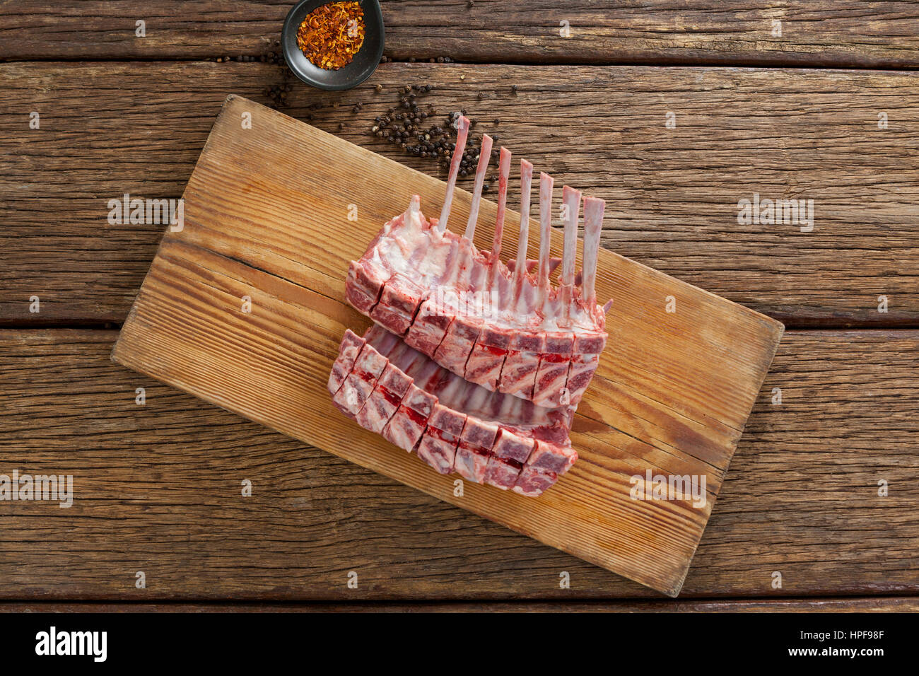 Rack de côtes sur planche de bois avec des épices contre fond de bois Banque D'Images