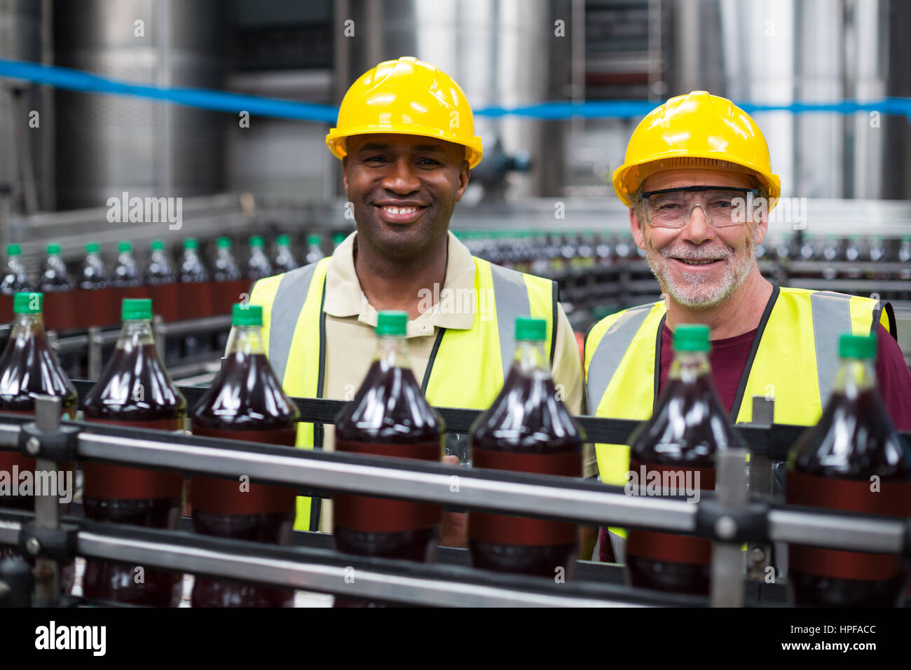 Les travailleurs d'usine souriant boissons surveillance ligne de production dans l'usine Banque D'Images