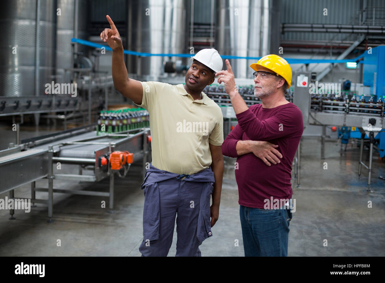 Deux travailleurs de l'usine vers le haut tout en discutant ensemble dans l'usine de production de boissons Banque D'Images