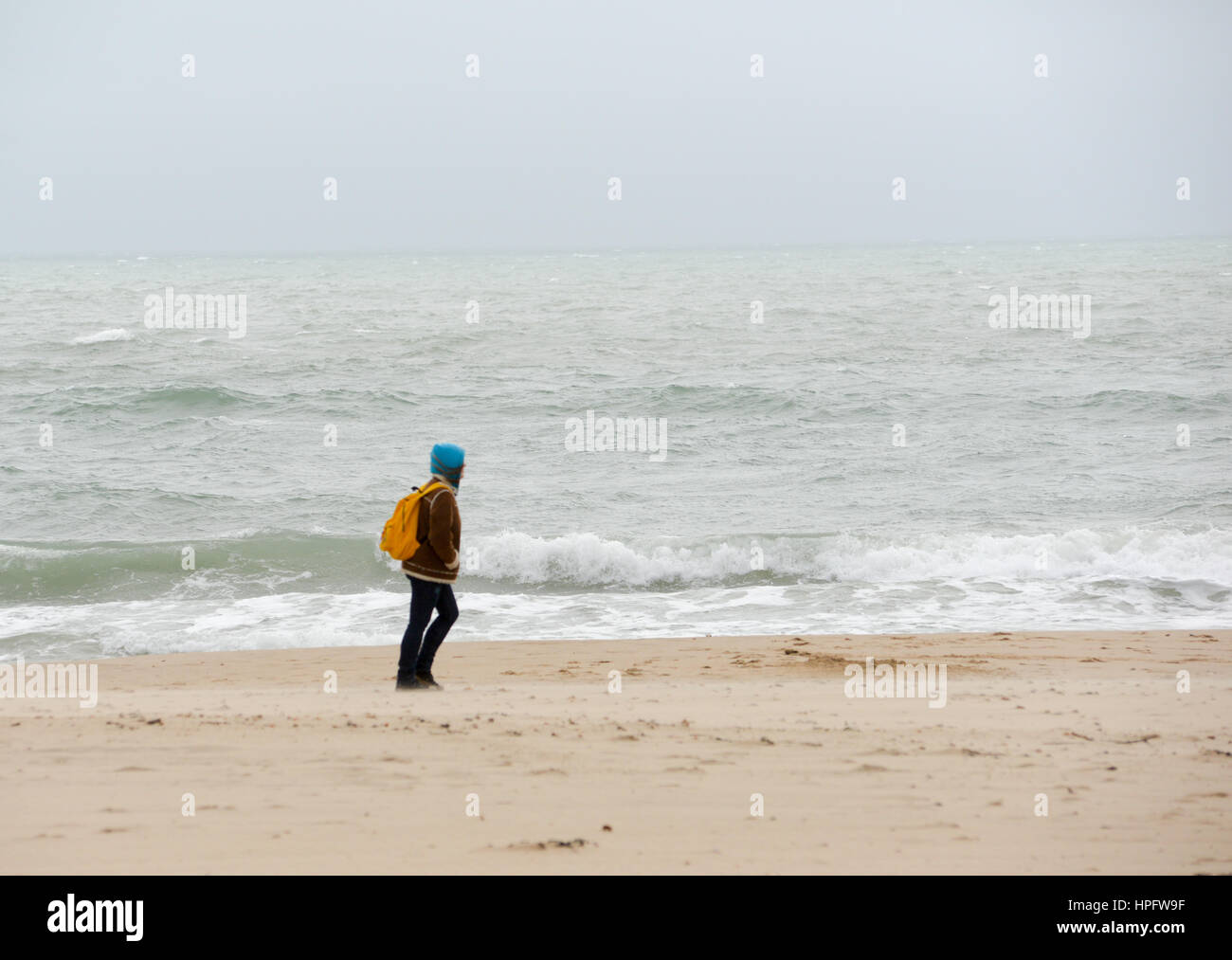 Femme marchant sur la plage et s'inclinant dans le vent pendant Storm Doris, février 2017, Bournemouth Banque D'Images