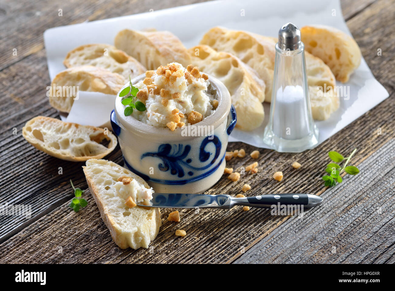 Saindoux copieux à Greaves et les oignons dans un pot grès rustique servi avec pain ciabatta italien sur une table en bois rustique Banque D'Images