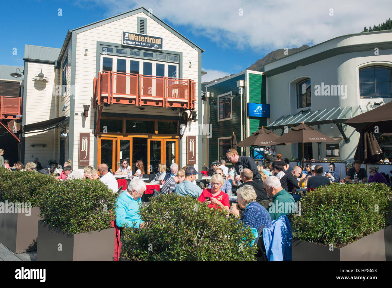 Queenstown, Otago, Nouvelle-Zélande. Les clients sur la terrasse animée de Pier 19, un restaurant et un café au bord du lac. Banque D'Images