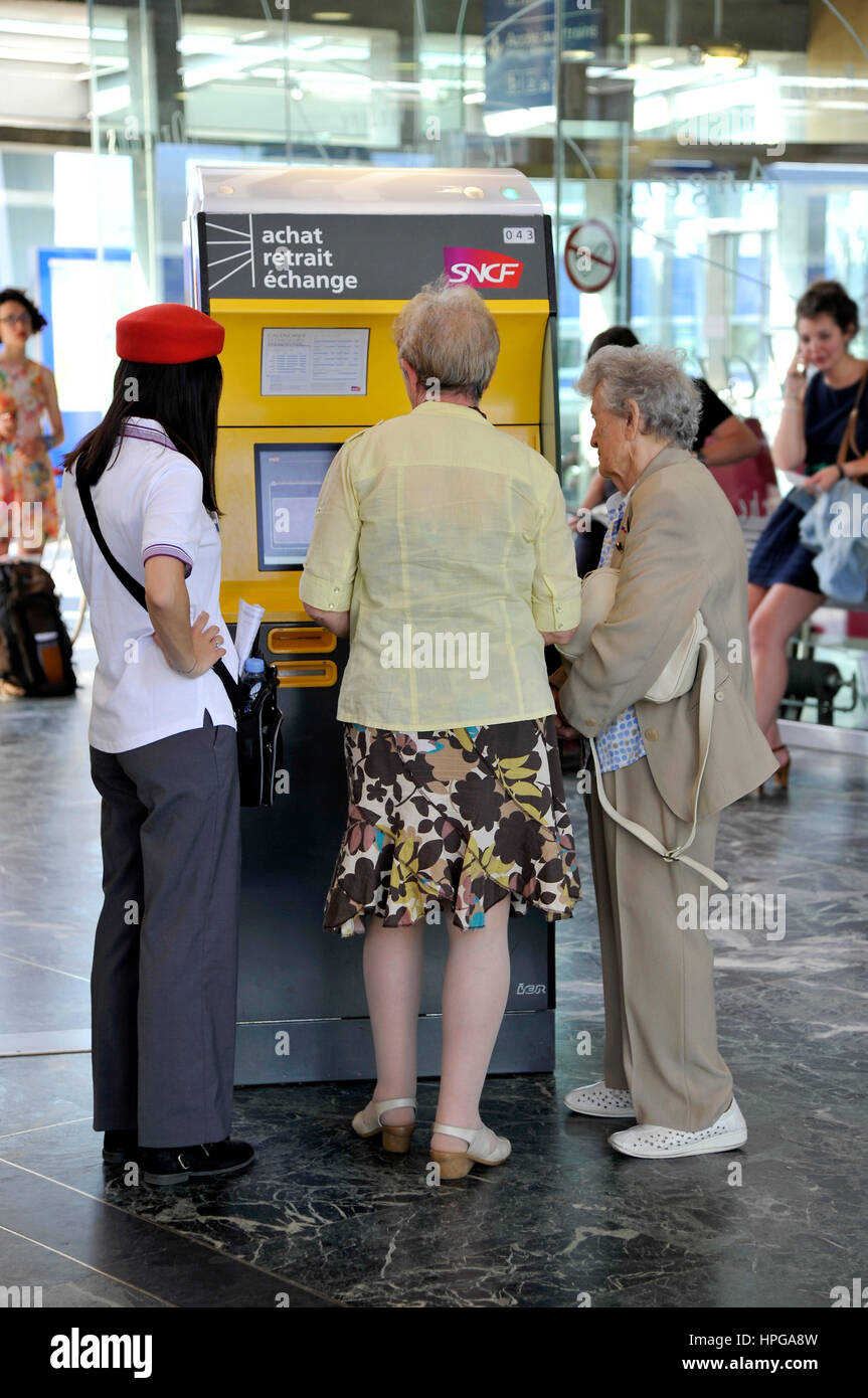 La France, l'ouest de la France, de la gare SNCF de Nantes,employé aidant les personnes âgées à acheter leurs billets à la machine de billets dans le hall de départ Banque D'Images