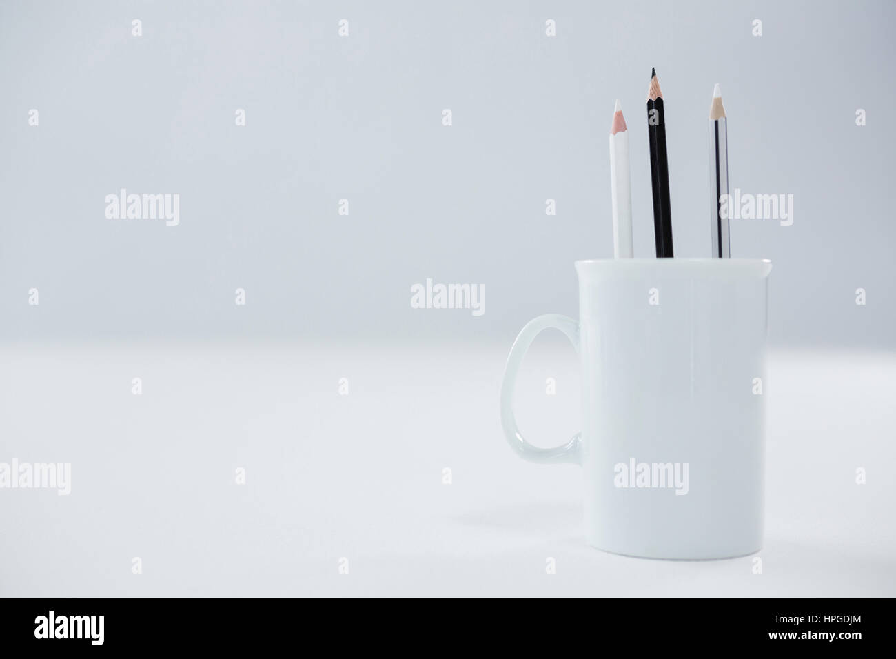 Crayons de couleur noir et blanc conservé dans mug sur fond blanc Photo