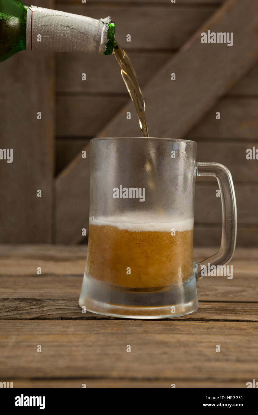 La bière est versé dans une tasse sur la table en bois Banque D'Images