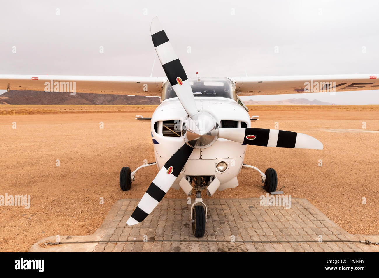 Un Cessna 210, l'inscription V5-KST, assis sur l'aérodrome près de Serra Cafema Camp de pleine nature de la Namibie. Il est peint dans les couleurs de l'air en milieu sauvage. Banque D'Images