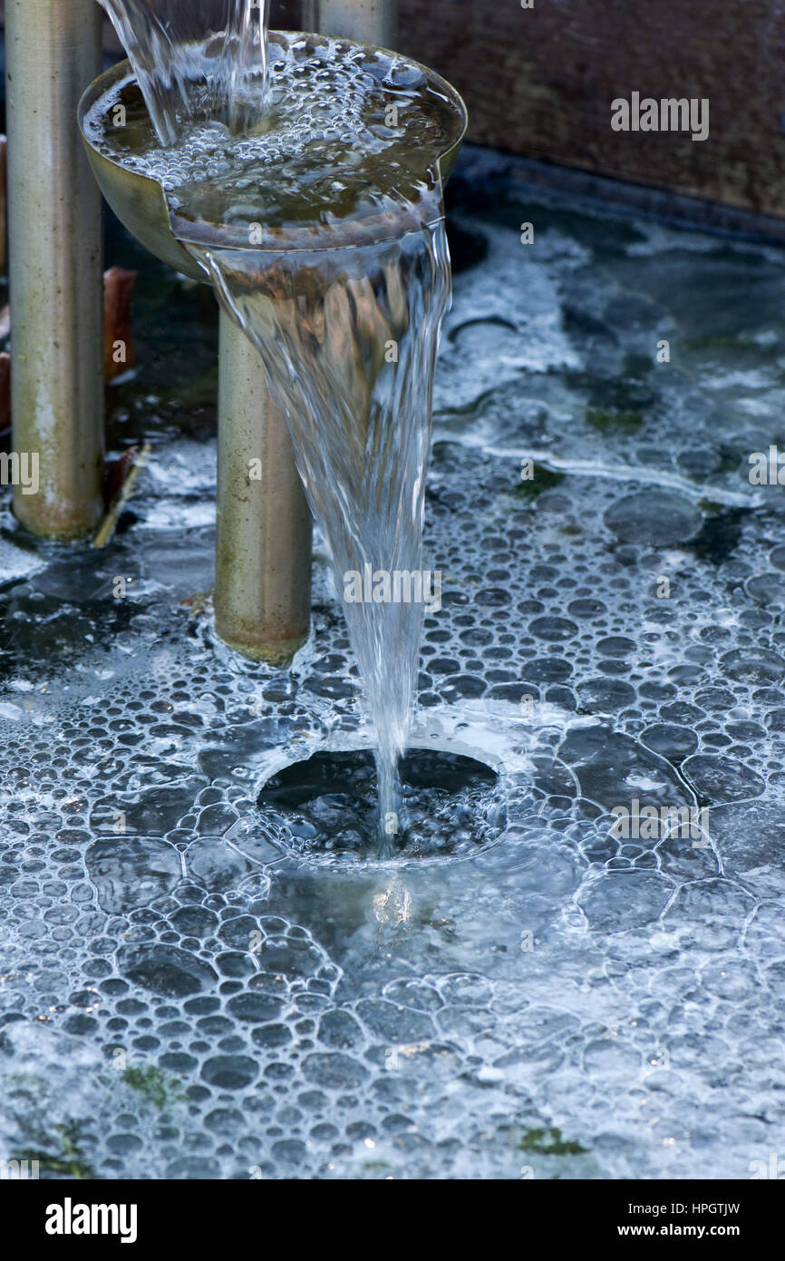 Dispositif de l'eau dans un étang de jardin d'eau en cascade à travers un trou dans la glace avec bulles formant sous Banque D'Images