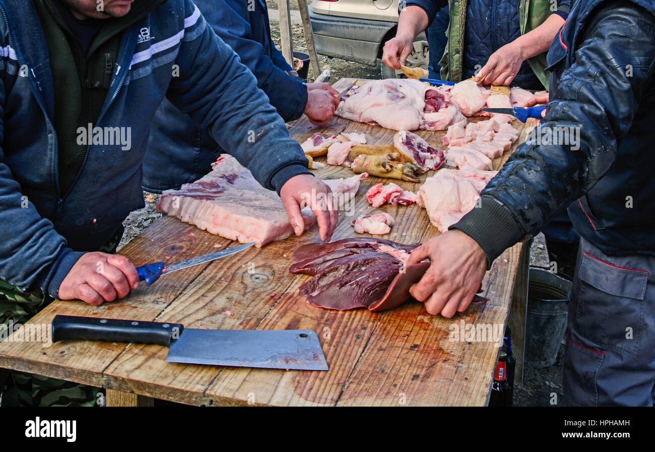 Les bouchers de groupe à l'extérieur sur une table de traitement de la viande de porc. Banque D'Images