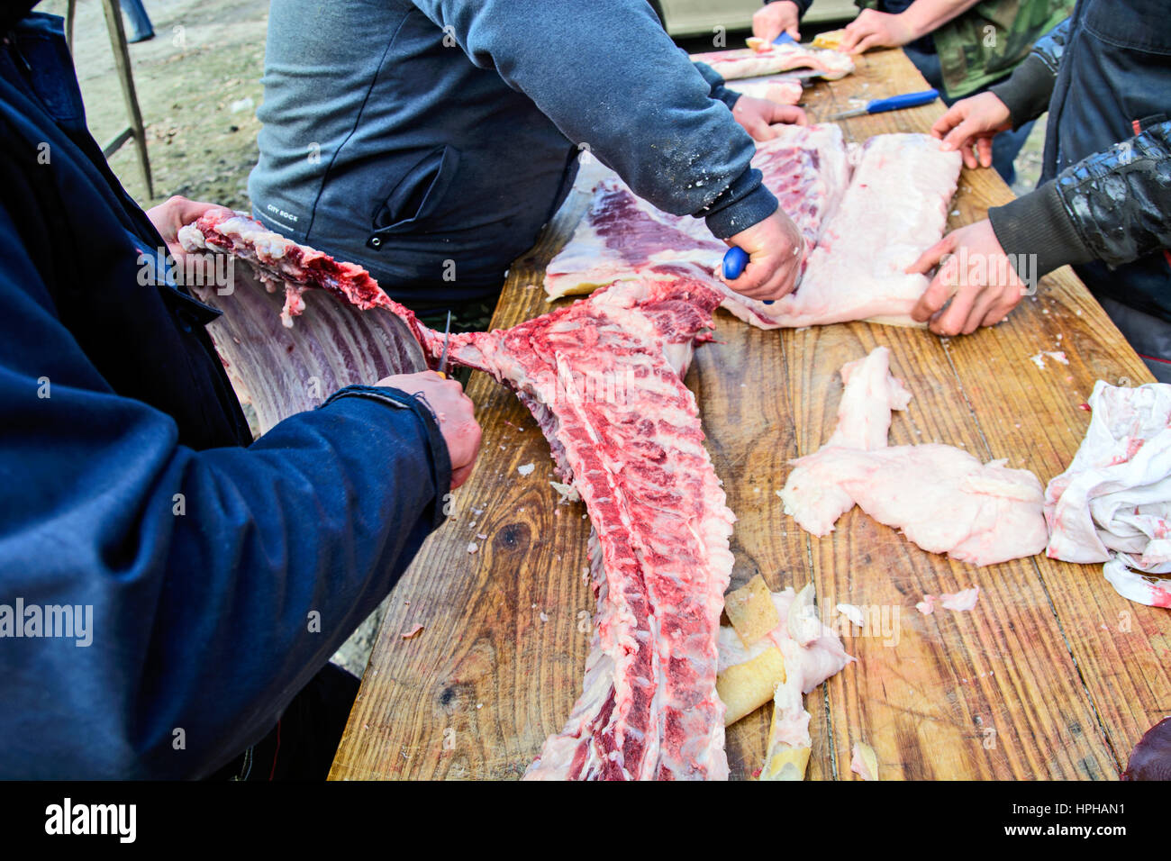 Les bouchers de groupe à l'extérieur sur une table de traitement de la viande de porc. Banque D'Images