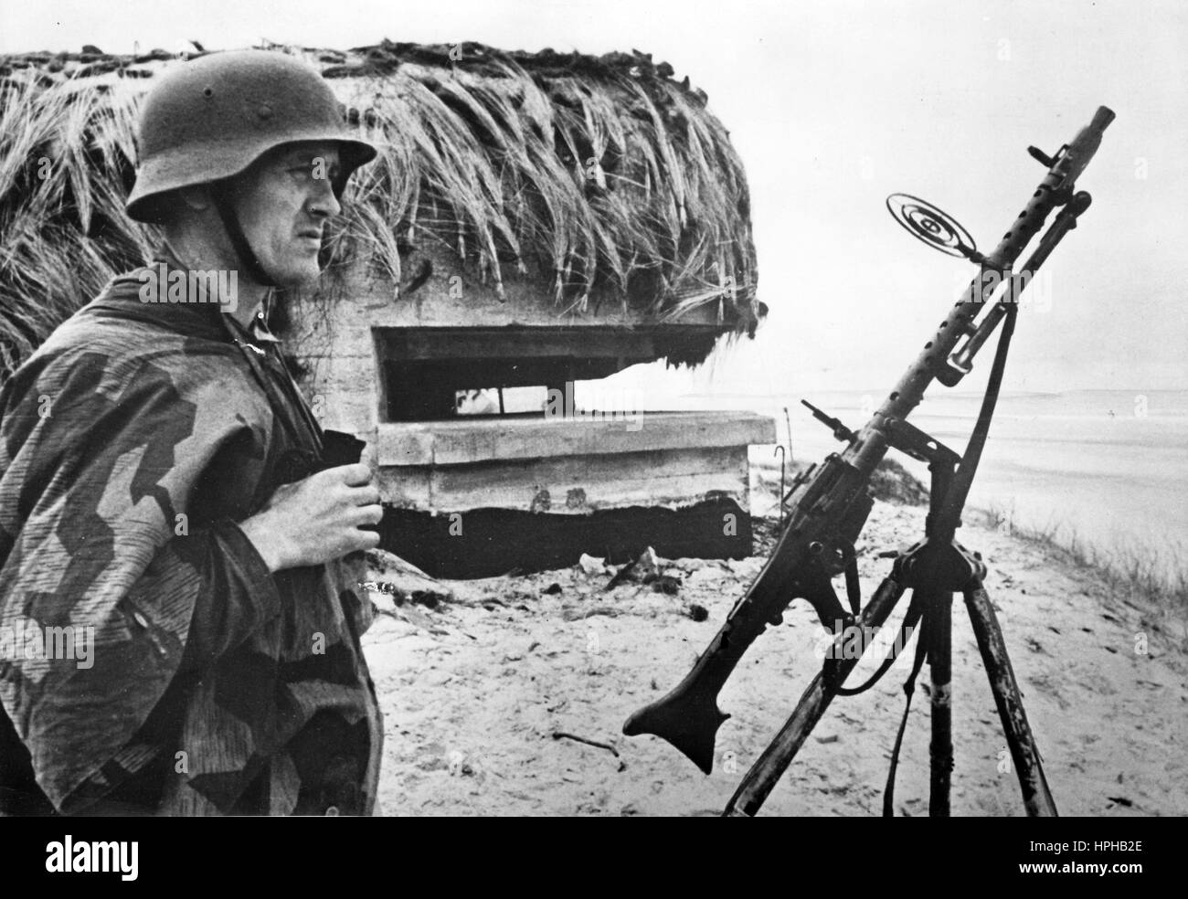 L'image de propagande nazie montre un poste de mitrailleuse Wehrmacht allemand devant un bunker camouflé sur le mur de l'Atlantique. Publié autour de 1943. Fotoarchiv für Zeitgeschichte - PAS DE SERVICE DE FIL - | utilisation dans le monde entier Banque D'Images