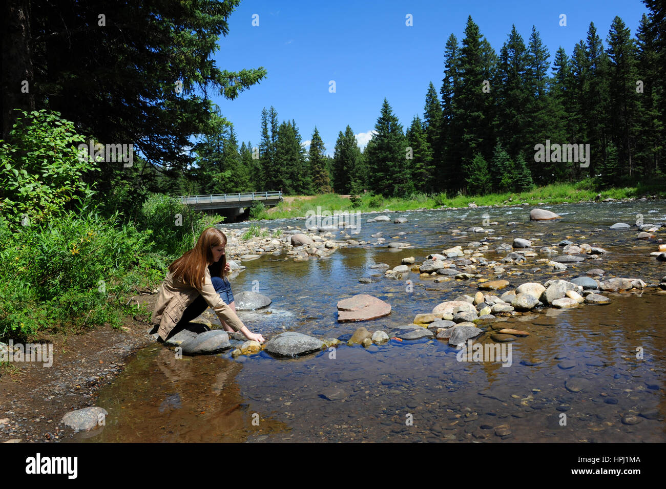 Jeune femme se trouve en dehors de la Gallatin River dans le Montana. Elle est pieds nus et seule avec ses pensées. Banque D'Images