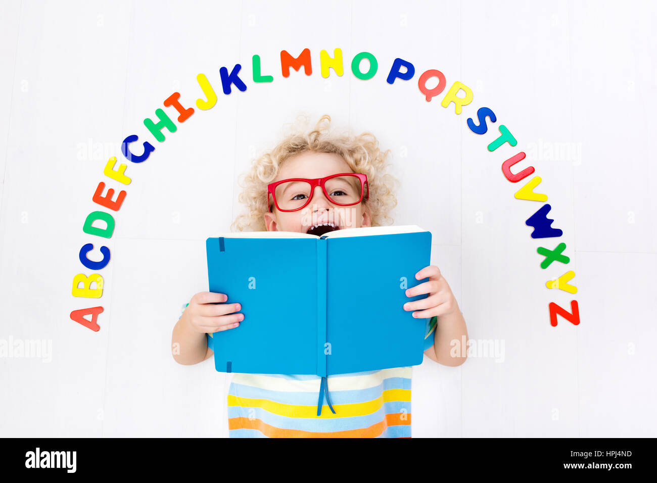 Heureux l'enfant d'âge préscolaire d'apprendre à lire et à écrire en jouant avec les lettres de l'alphabet romain coloré. Abc de l'éducation des jouets et livres pour enfants. Élève de l'école Banque D'Images