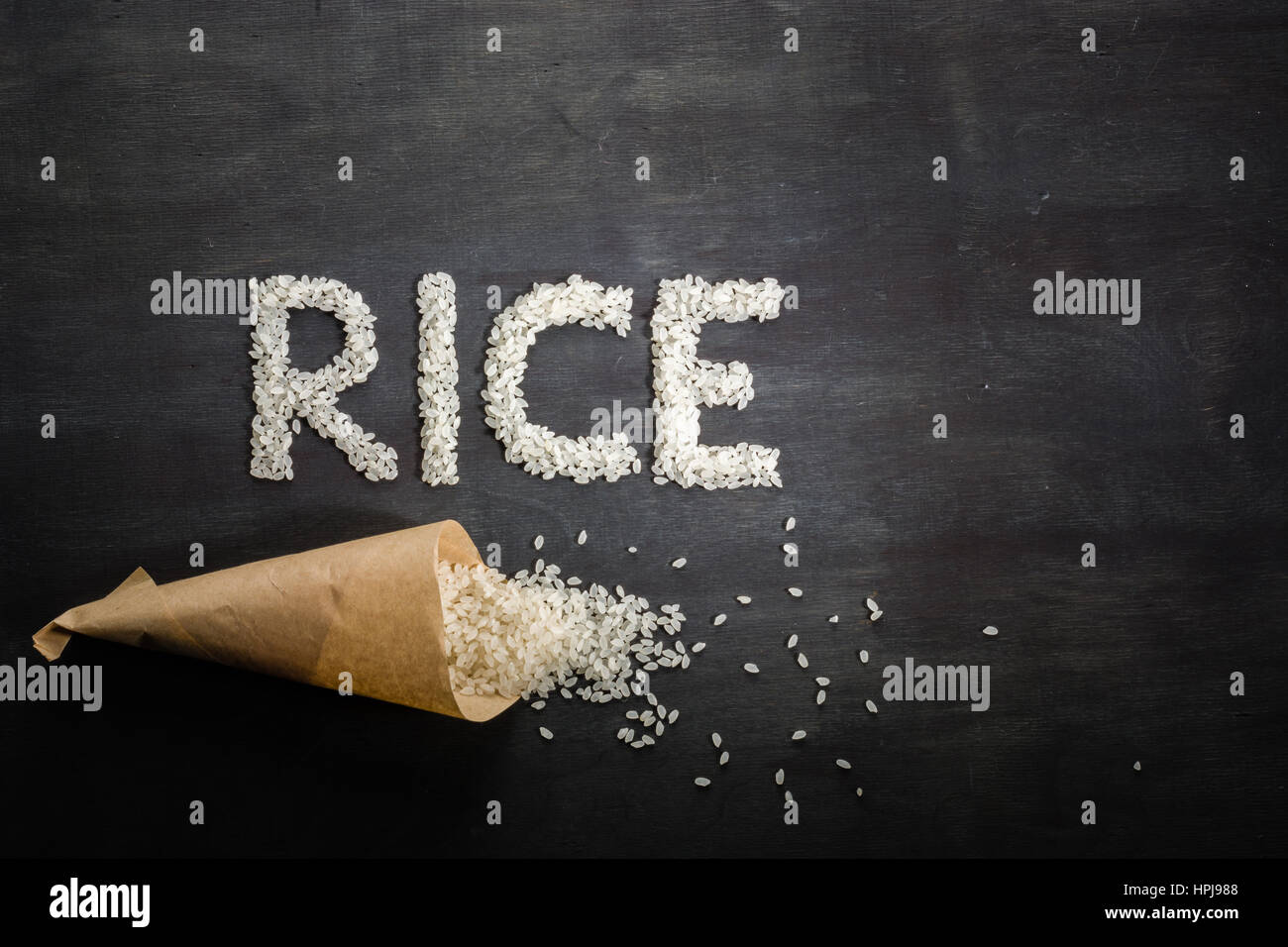 Riz blanc éparpillés sur la table en bois sombre d'un sac en papier. Vue de dessus. L'espace pour le texte. Banque D'Images