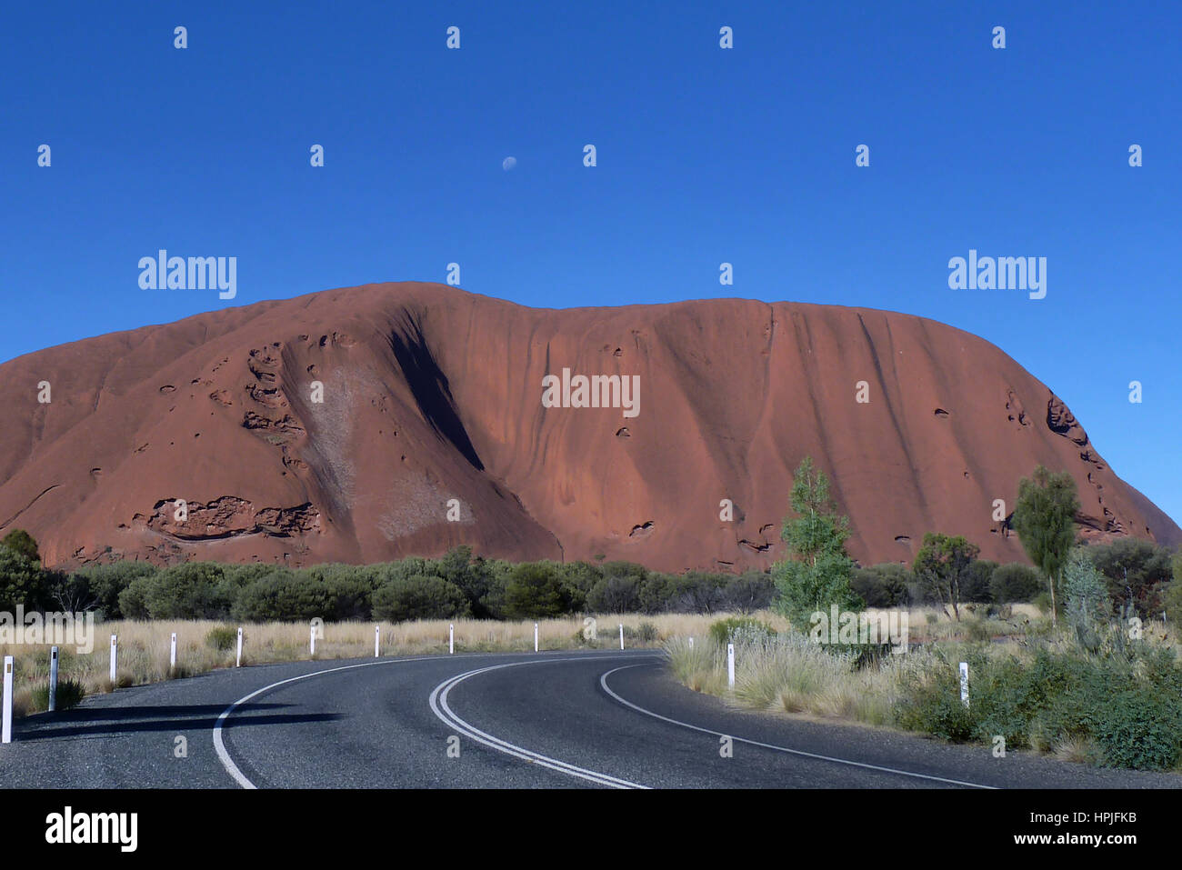 Ayers Rock contrastée par ciel bleu avec la lune visible. Banque D'Images