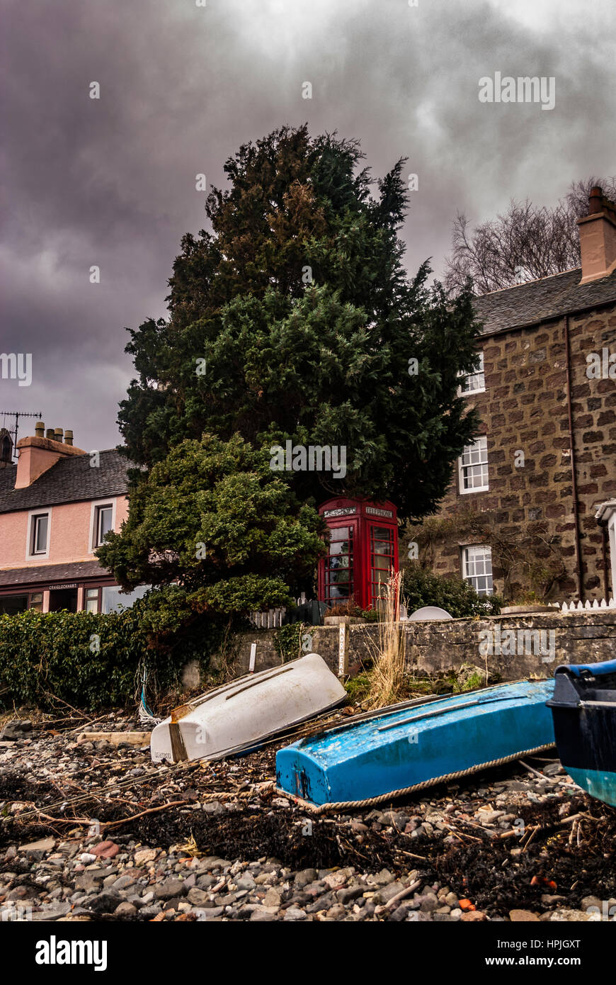 Bateaux et téléphone fort sur le quai à Portree Harbour de la plage, à la recherche à la ville. Banque D'Images