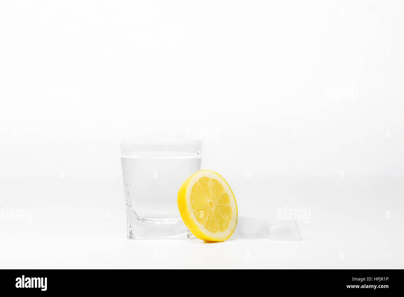 Morceau de citron et glace avec verre d'eau isolé sur blanc Banque D'Images