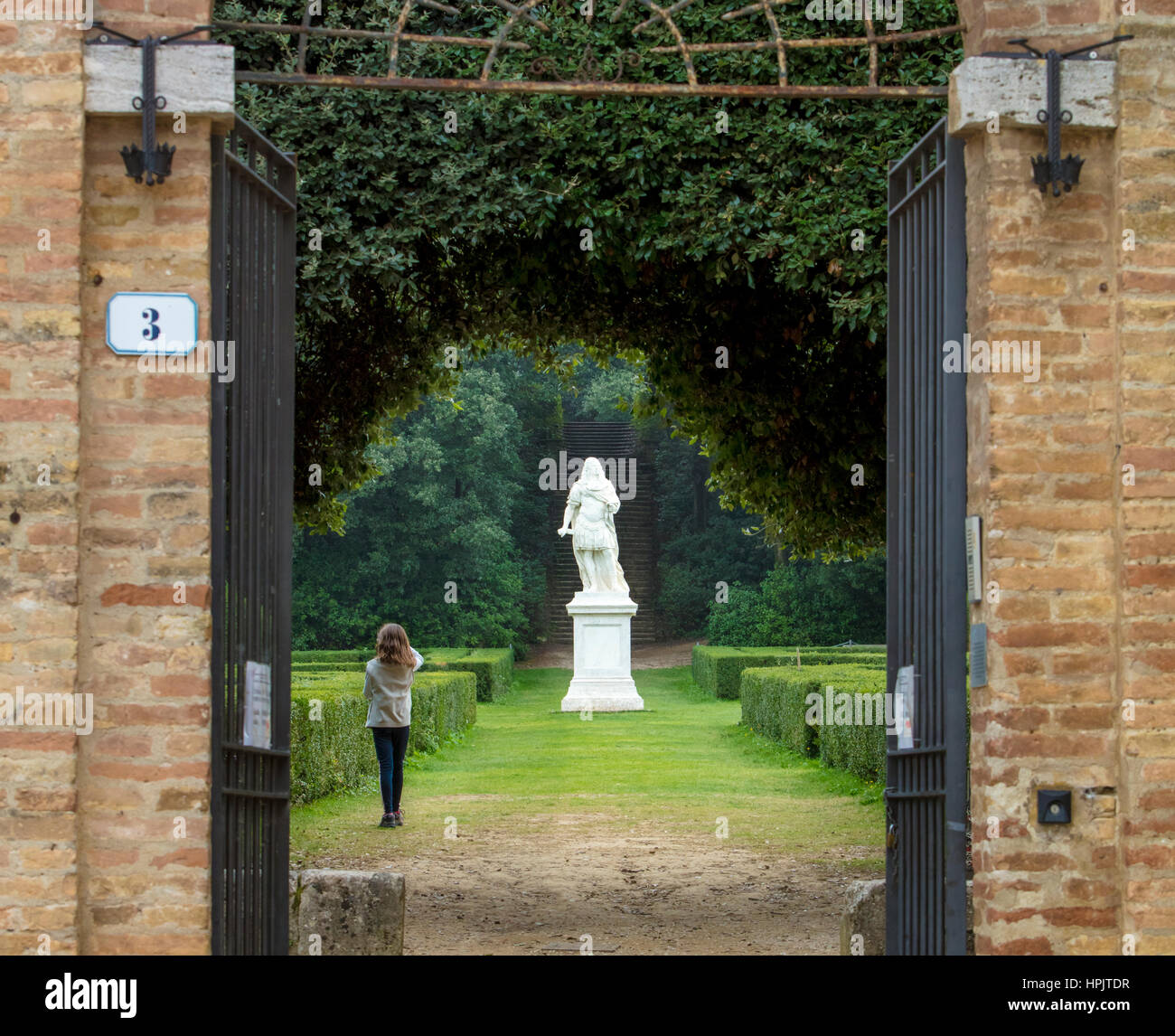Jeune fille à l'entrée de l'Horti Leonini Jardin avec la statue du Grand-duc Cosme III de Médicis, San Quirico d'Orcia, Toscane, Italie Banque D'Images