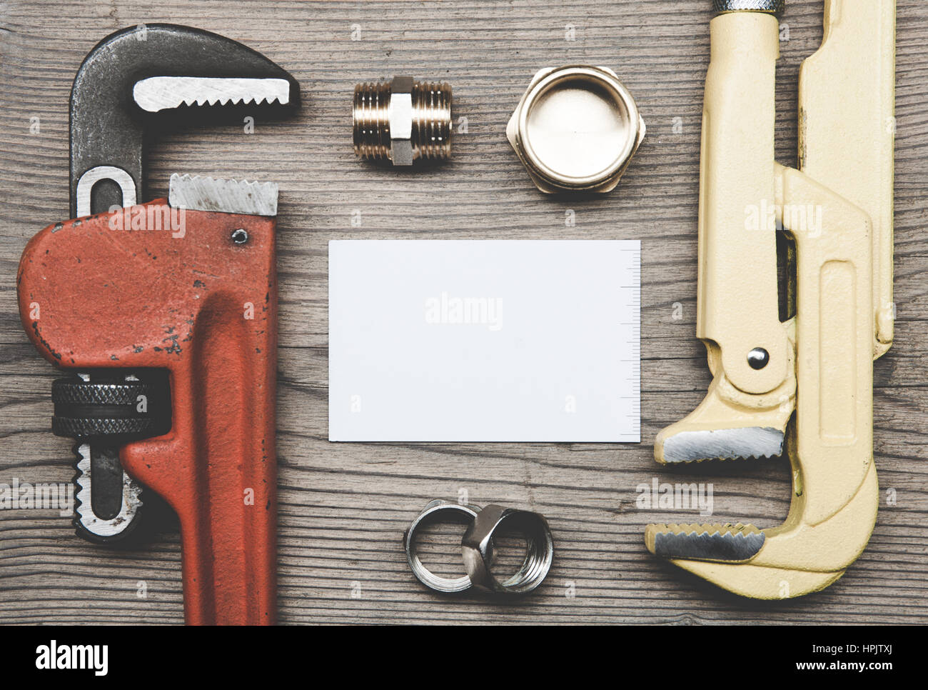 Outils de plomberie tuyaux raccords et carte d'affaires sur le fond de la surface en bois Banque D'Images
