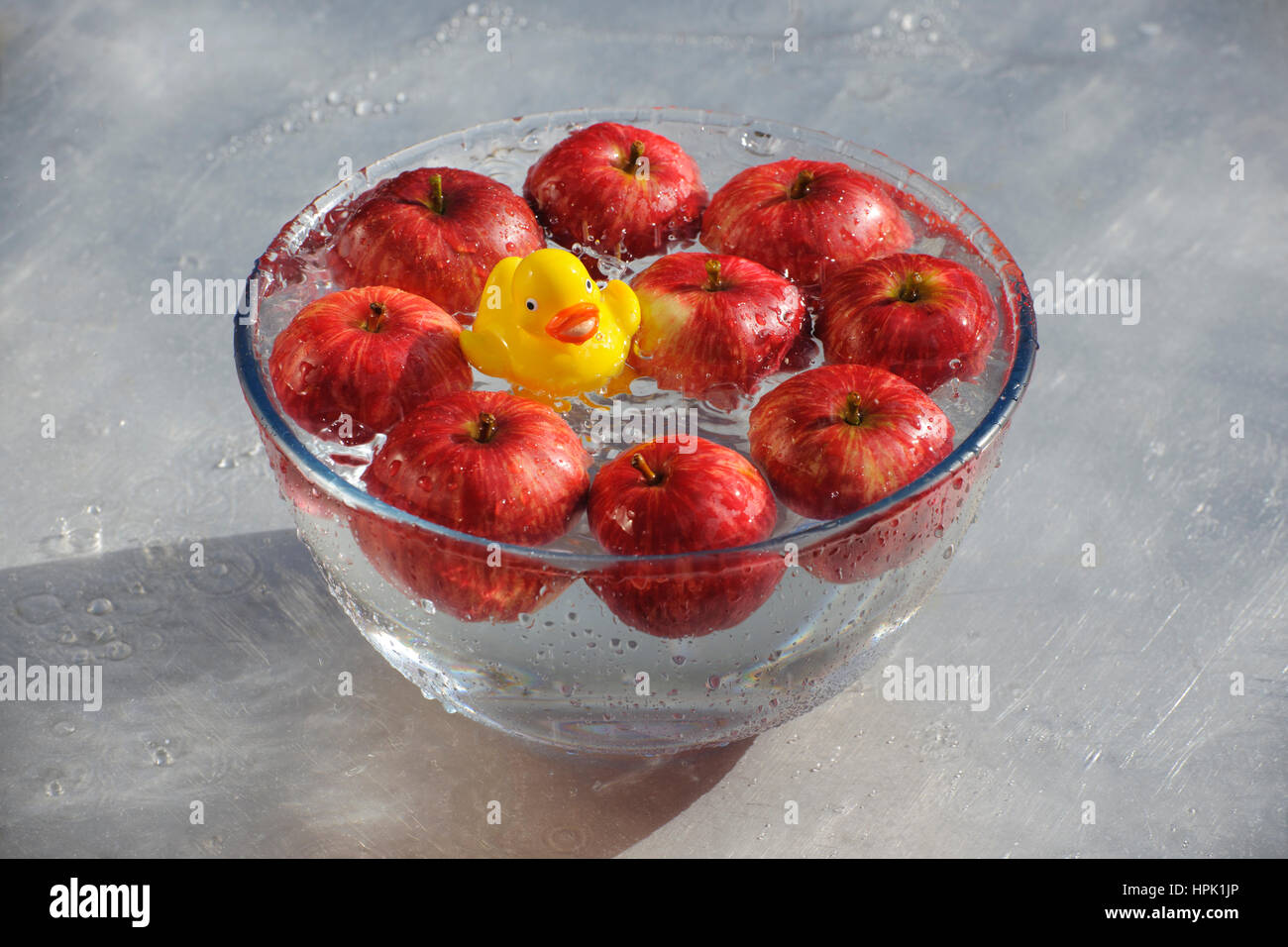 L'atténuation pour les pommes. Canard en plastique jaune, bien jouer dans un bol d'eau et de pommes rouges. Banque D'Images