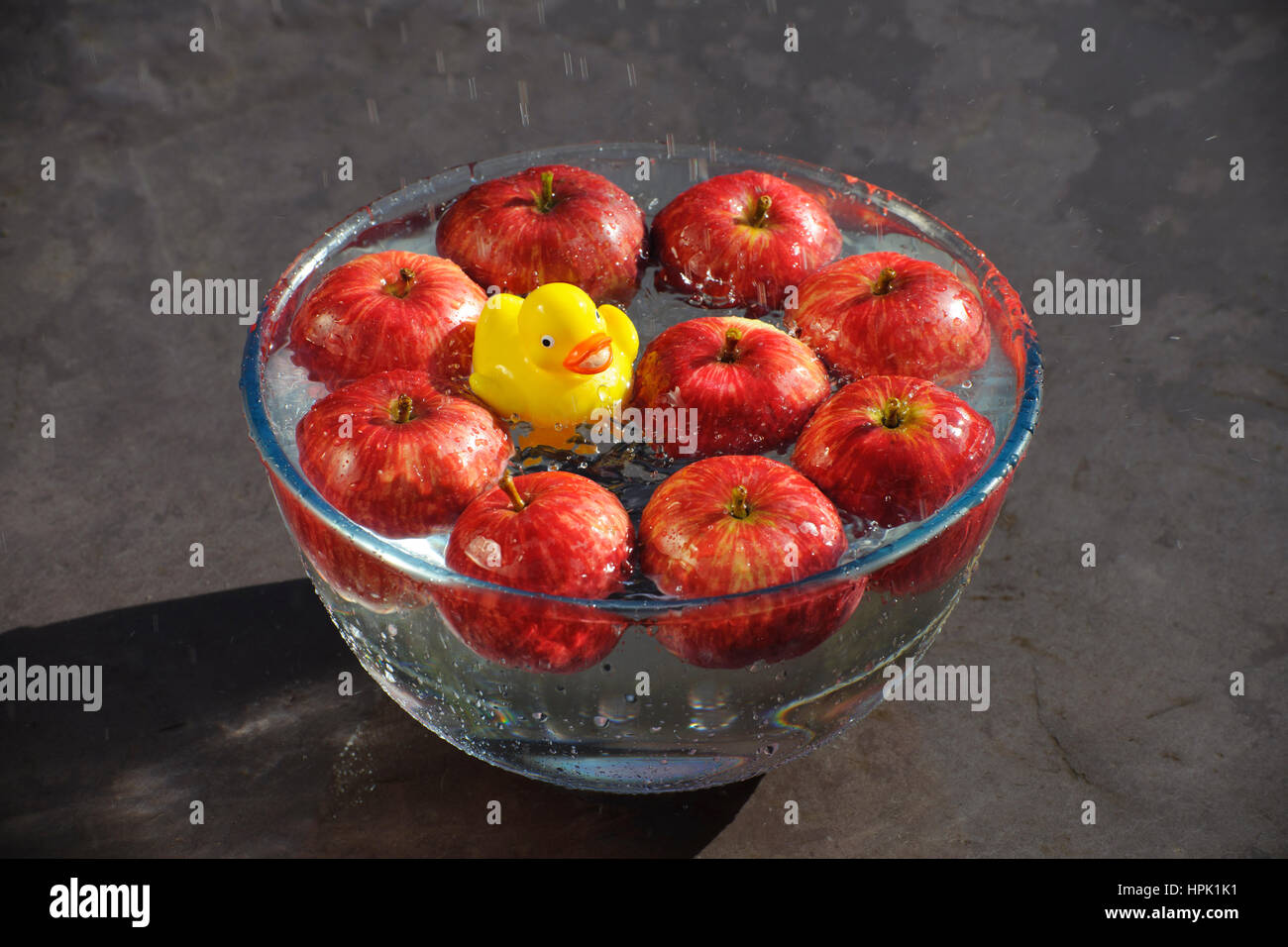 L'atténuation pour les pommes. Canard en plastique jaune, bien jouer dans un bol d'eau et de pommes rouges. Banque D'Images